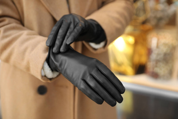 Mujer poniéndose guantes de cuero con estilo al aire libre, primer plano de las manos - Foto, imagen