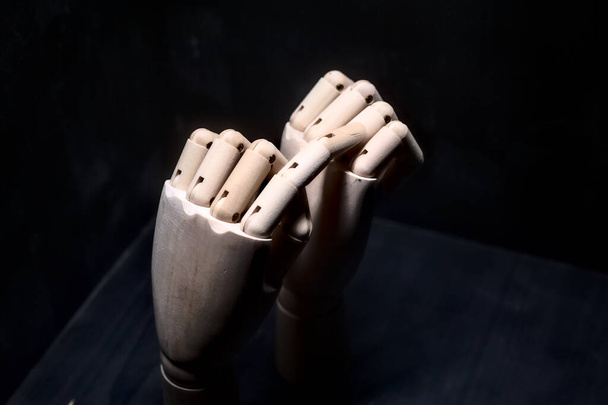 Een houten hand die met zijn wijsvinger een andere houten hand stevig gesloten raakt - Foto, afbeelding