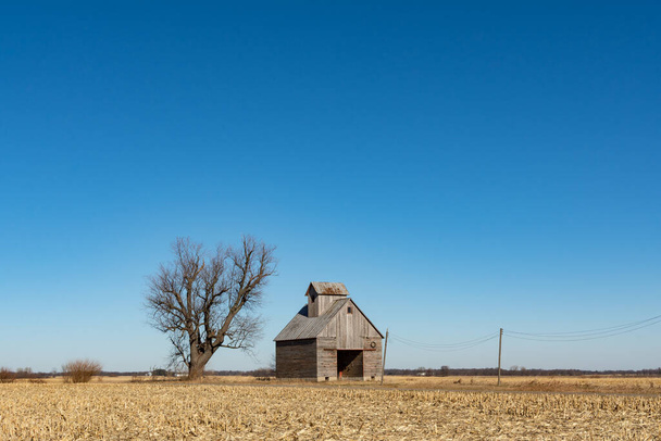 不毛の冬の風景の中に隔離されたトウモロコシのカニの納屋。米国イリノイ州. - 写真・画像