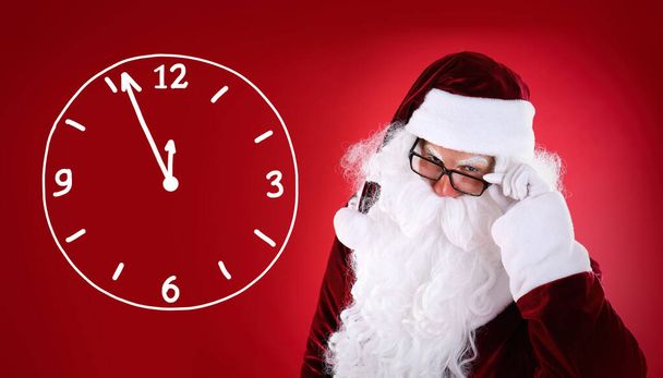 Christmas countdown. Clock showing five minutes to midnight near Santa Claus on red background - Foto, imagen