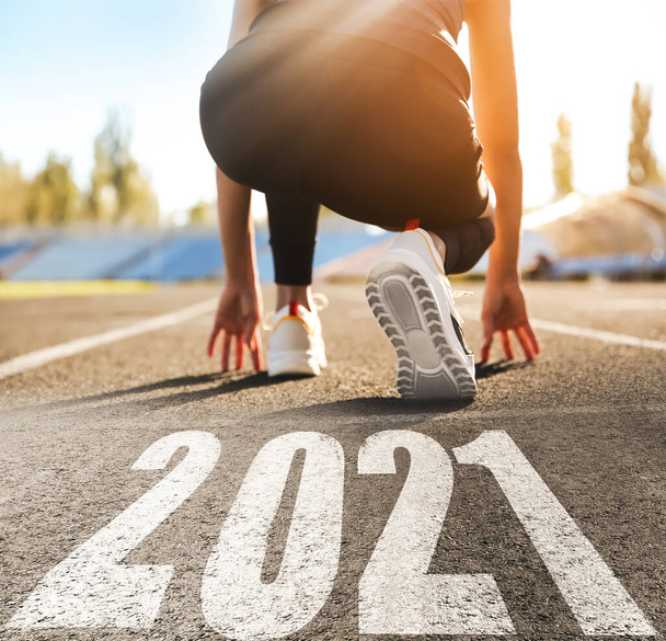 Start new year with fresh vision and ideas. Sporty woman ready for running near 2021 numbers on road, closeup - Foto, afbeelding
