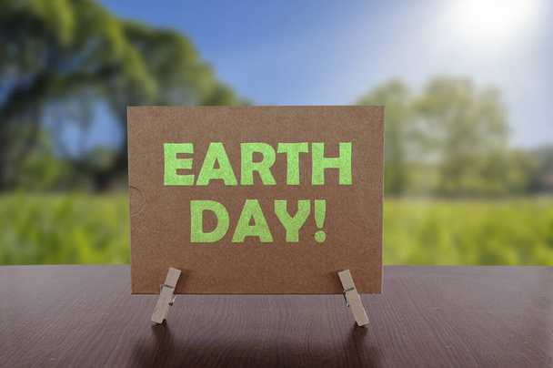 Earth day tekst op kaart op tafel met zonnige groene parkachtergrond. Ecologisch concept, recyclage, hergebruik, vermindering van afval. - Foto, afbeelding