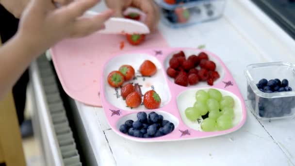 Mãos femininas cortando morangos e colocando-os em uma bandeja rosa - Filmagem, Vídeo