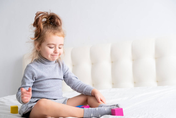 bambina che gioca giocattoli di legno a casa sul letto. Home attività per bambini. - Foto, immagini