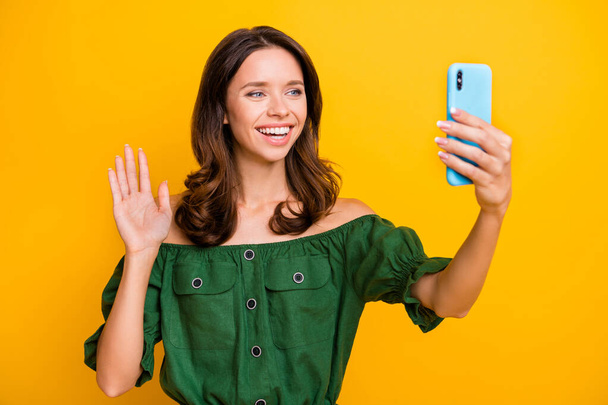 Photo of pretty attractive young woman hold phone take selfie wave hello isolated on yellow color background - Foto, Bild