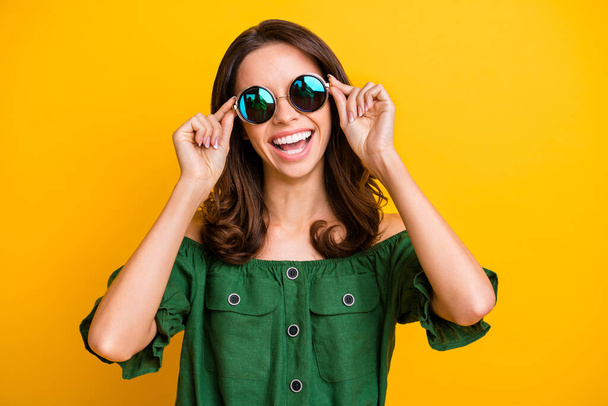 Fénykép boldog szép, vidám fiatal nő visel érintés napszemüveg sugárzó mosoly elszigetelt ragyogás sárga színű háttér - Fotó, kép