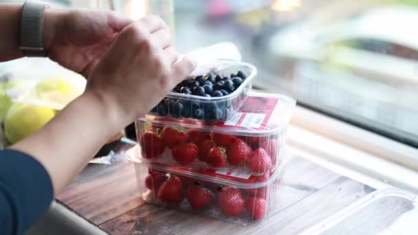 Female hands pouring blueberries into a small plastic container - Footage, Video
