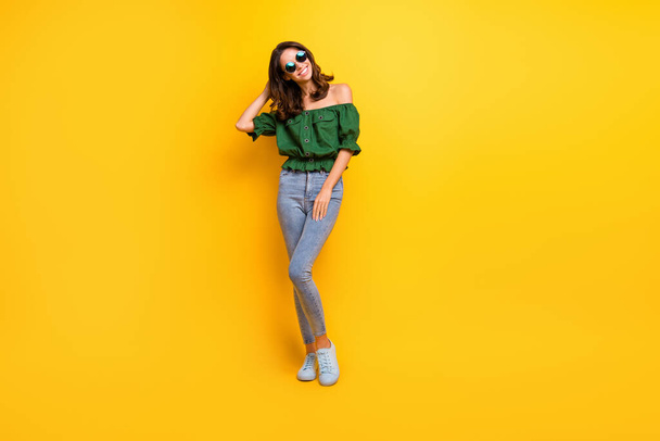Full length photo of attractive brunette young happy woman touch hair wear sunglass isolated on yellow color background - Zdjęcie, obraz