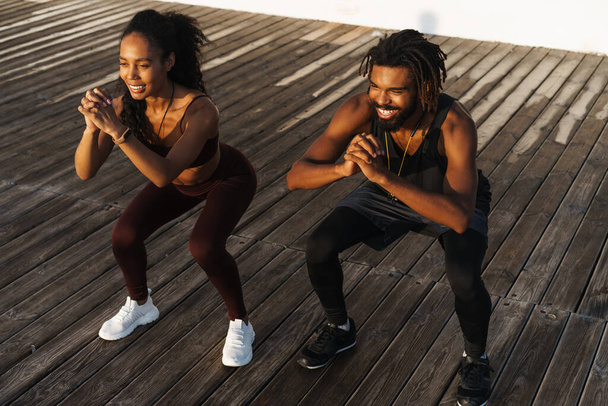 Young beautiful happy african american man and woman doing workout outdoors - Фото, зображення