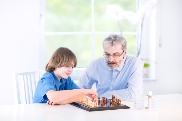 Мальчик играет в шахматы со своим дедушкой
 - Фото, изображение