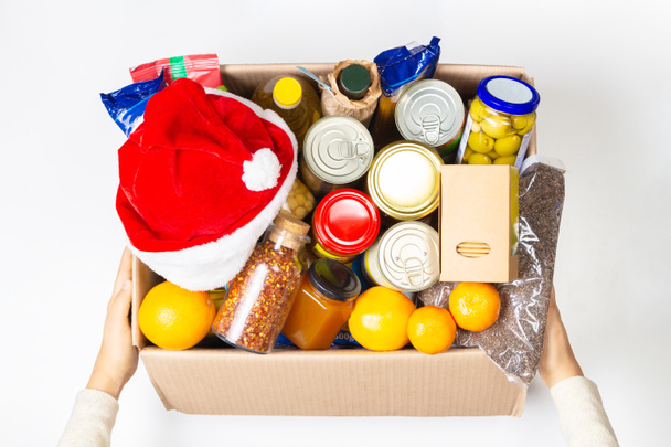 Χριστουγεννιάτικη δωρεά. Κουτί δωρεών τροφίμων με προϊόντα παντοπωλείου σε λευκό φόντο. Άνω όψη - Φωτογραφία, εικόνα