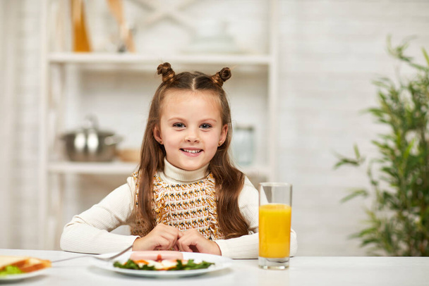 little child girl having breakfast - fried egg and orange juice - 写真・画像