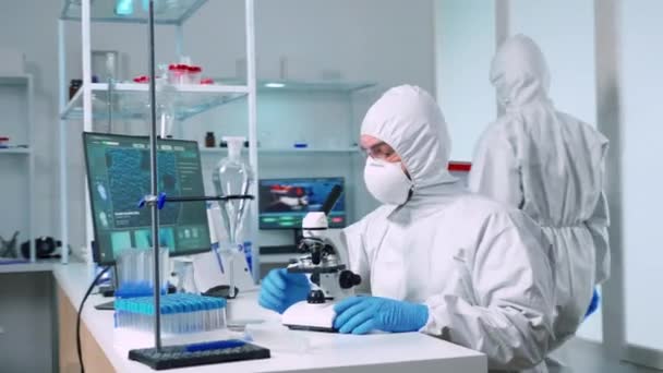 A laboratóriumban dolgozó tudós ppe öltönyben, modern mikroszkóppal - Felvétel, videó