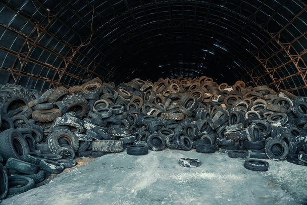 Grande pila di vecchi pneumatici usati per auto e camion in hangar abbandonato - Foto, immagini