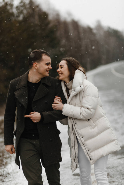 Nuori ja nainen kulkevat talvitietä ja hymyilevät toisilleen. Rakkaus, suhde, talvilomat. Talvi pari valokuva ideoita - Valokuva, kuva
