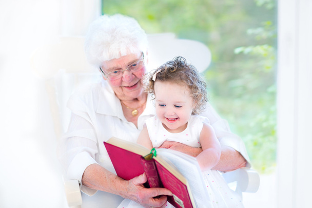 Dame aînée lisant un livre à sa petite-fille
 - Photo, image