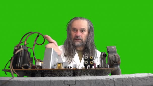 Crazy repairman engineer talks and rejoices about difficulties of repairing the motherboard, solders parts and hits with hammer. Green background - Footage, Video