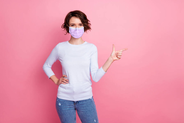 Positive girl promoter point index finger empty space wear respiratory pullover sweater isolated pink color background - 写真・画像
