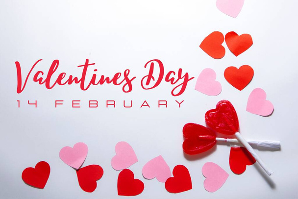 Merkez düzlem. İki kalp şeklinde lolipopu olan kırmızı ve pembe kalpli beyaz bir arka plan. Sevgililer günü ve romantik aşk konsepti. Metin - Fotoğraf, Görsel