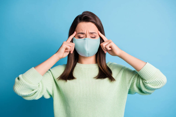 Photo of exhausted lovely girl eyes closed fingers head frown wear blue fabric face mask isolated blue color background - Photo, image