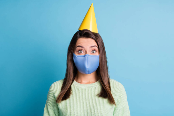 Photo portrait of excited smiling girl wearing yellow birthday headwear blue fabric face mask isolated on pastel blue colored background - Foto, Imagem