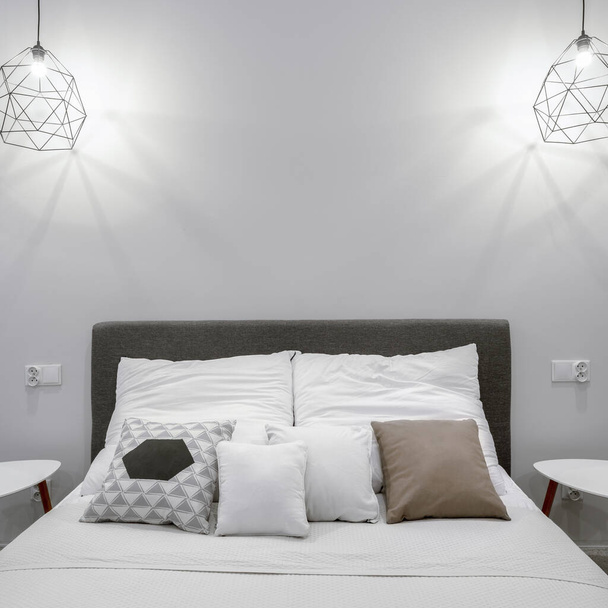 Comfortable double bed, two bedside tables and two pendant lamps in white bedroom - Foto, Bild