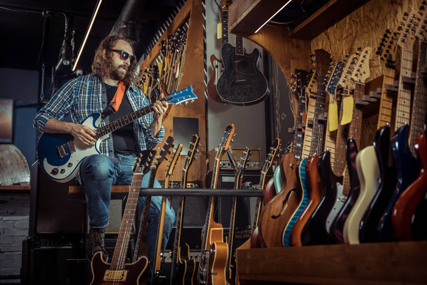 Guitarrista está tocando guitarra elétrica em uma loja de instrumentos musicais. - Foto, Imagem
