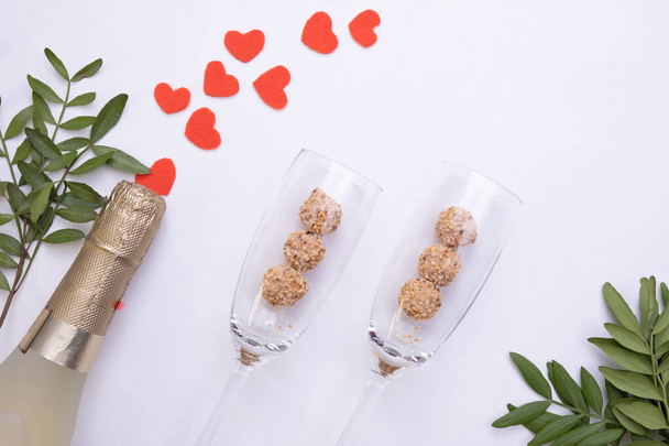 bottle of champagne, wine glasses, candies and red hearts on a white background, top view - Fotoğraf, Görsel