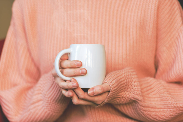 Girl holding white ceramic mug with hot beverage coffee or tea, toned picture - Foto, Imagem