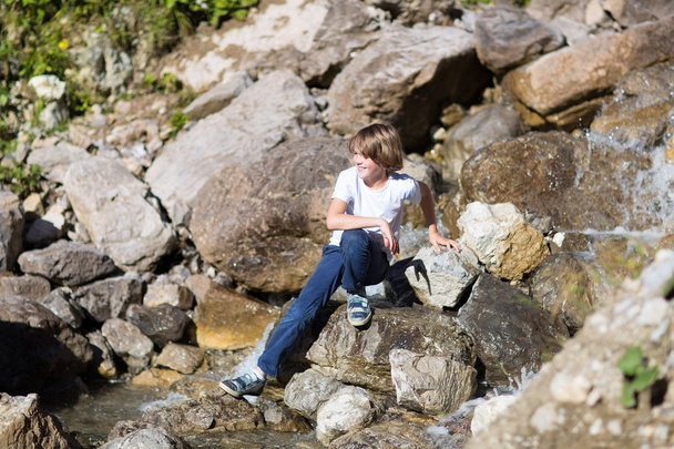Хлопчик-підліток перетинає маленьку річку
 - Фото, зображення