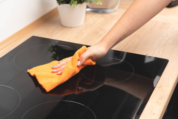 Woman cleaning induction stove. Modern kitchen with induction hob - Foto, afbeelding