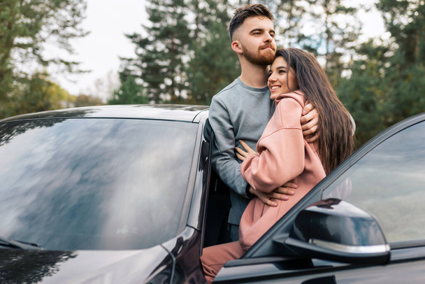 Όμορφο ζευγάρι στέκεται στην πόρτα του αυτοκινήτου αγκαλιάζει - Φωτογραφία, εικόνα