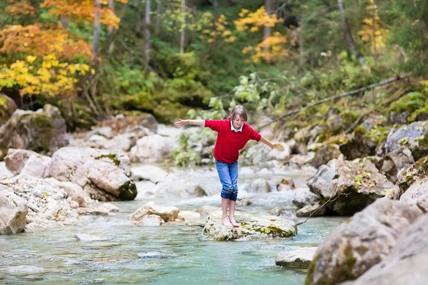 少年ジャンプする野生の山の川を横断しよう - 写真・画像