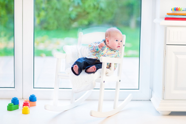 Menino recém-nascido em uma cadeira de balanço branca
 - Foto, Imagem