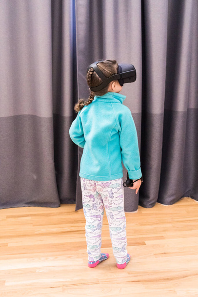Little girl playing VR kids game in the living room. - Foto, Imagen