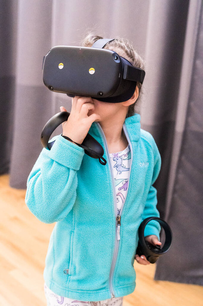 Девочка играет в детскую игру виртуальной реальности в гостиной. - Фото, изображение