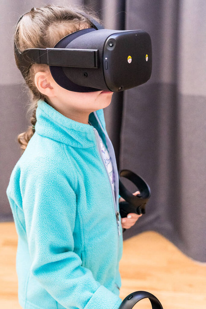 Κοριτσάκι που παίζει VR παιδικό παιχνίδι στο σαλόνι. - Φωτογραφία, εικόνα