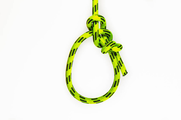 boeglijn. Een knoop van synthetisch geel touw geïsoleerd op witte achtergrond. De Bowline is een oude en eenvoudige knoop die gebruikt wordt om een vaste lus te vormen aan het einde van een koord. - Foto, afbeelding