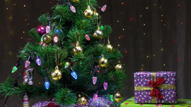Groene kerstboom en prachtige geschenken op de achtergrond van knipperende slingers - Video