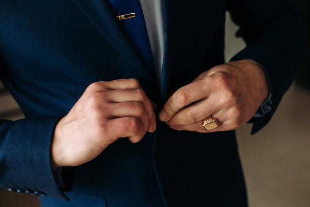 A stylish man in a blue suit fastens his buttons, preparing to leave. Preparing for the wedding - Photo, image