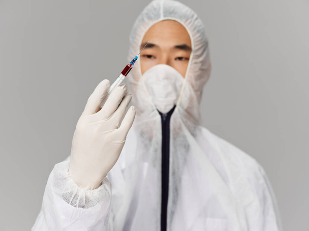 Asistente de laboratorio masculino que investiga análisis de una jeringa en las manos de una vacuna de prueba - Foto, imagen