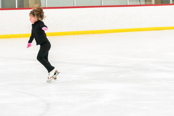 Kleine schaatsster oefent haar elementen in de ochtend kunstschaatstraining. - Foto, afbeelding