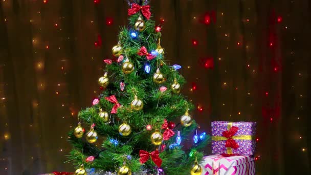 Prachtig versierde kerstboom en geschenken tegen de achtergrond van knipperende lichten - Video