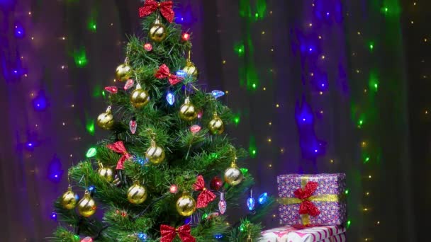 Sapin de Noël magnifiquement décoré et cadeaux sur fond de lumières clignotantes - Séquence, vidéo