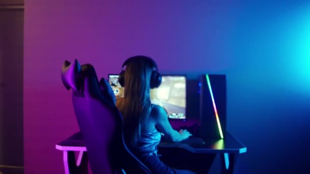 Giovane bionda gamer donna si siede sulla sedia in neon gaming club - Filmati, video