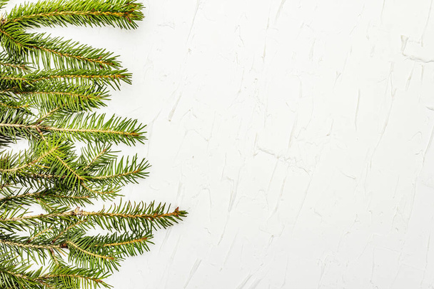 Border of Christmas tree branches on white putty background. New Year greeting card concept, top view - Foto, Imagem