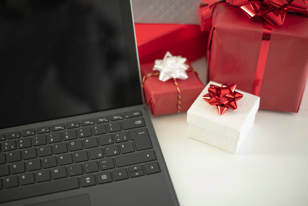 achats en ligne, cadeaux en ligne, ordinateur portable et boîtes cadeaux assortis sur un fond blanc chaud - Photo, image