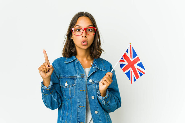 Beyaz arka planda izole edilmiş İngiliz bayrağı tutan genç Latin bir kadının harika bir fikri var, yaratıcılık kavramı.. - Fotoğraf, Görsel