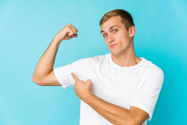 Young caucasian handsome man showing strength gesture with arms, symbol of power - Fotoğraf, Görsel