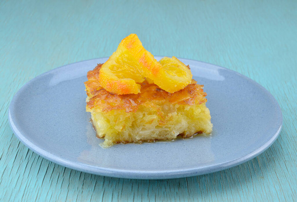 Pezzo di torta all'arancia in piatto con fetta di torsione arancione sulla parte superiore - Foto, immagini